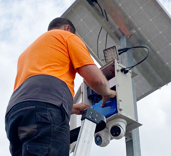 Man fitting a battery into a security camera tower control box