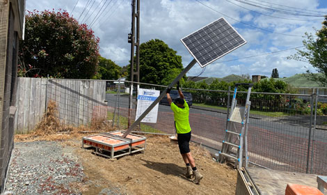 Man lifting a camera pole with solar panel attached into place